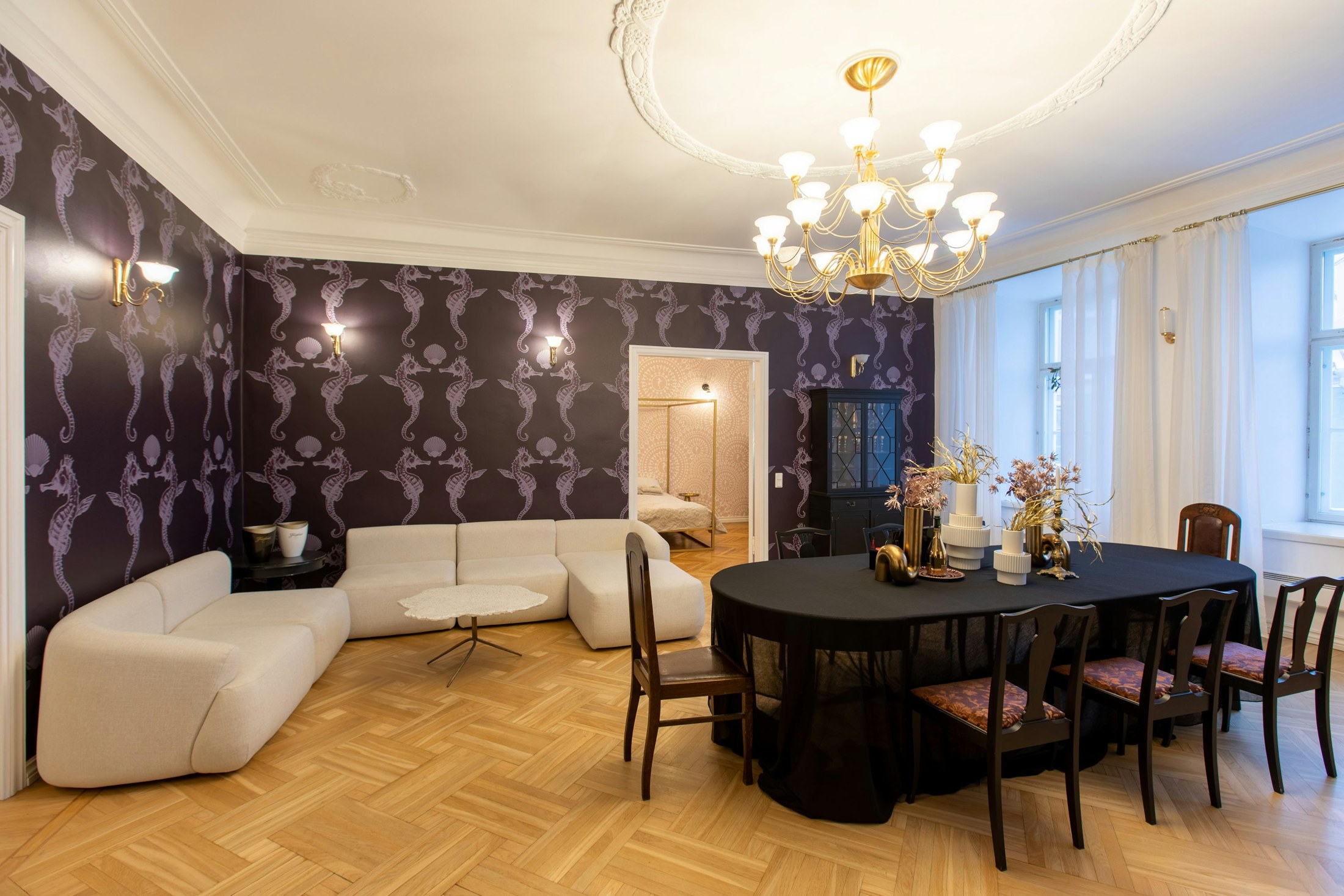 Dark repeating wallpaper surrounding a lounge with curved cream sofas